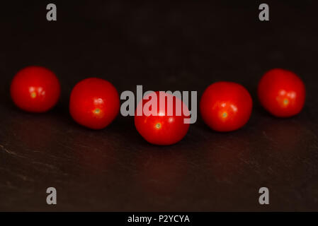 Red baby plum tomatoes isolated on a dark background on a slate surface. Fruit healthy eating concept Stock Photo