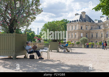 Paris, France - June 15, 2108: Elderly woman enjoys reading in the shade in Luxembourg Garden or Jardin du Luxembourg in sunny weather Stock Photo