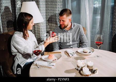 a beautiful brunette gives a gift to her boyfriend in a restaurant on a date Stock Photo