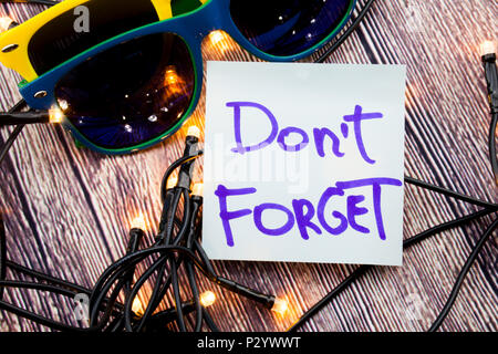 A piece of chart having words Do not Forget is present with two different colored glasses and lights around . Thre note in the picture remind someone  Stock Photo
