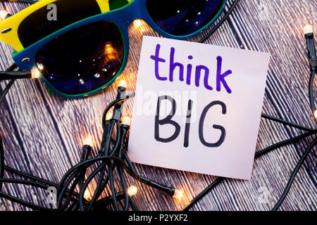 Think big handwritten words on white paper with wooden bark as background. Positive messages on flat lay concept with retro background. Positive moral Stock Photo