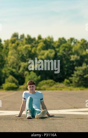 Young adult male sitting outside in the sun Stock Photo
