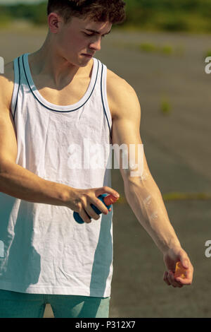 Young adult male putting on sun cream outside in the sunshine Stock Photo