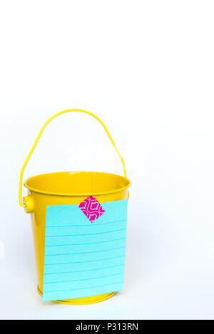 Bright yellow metal pail with aqua colored lined paper taped to front with pink washi tape on solid white background Stock Photo