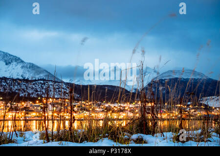 The city lights of Ushuaia are reflected in the water of the closed bay. Winter has come and snow covers the mountains and the valley. Stock Photo