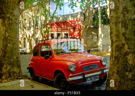 An elegant FIAT 600 stands on a large avenue in the beautiful old town of Colonia del Sacramento. Light and shadow seem to be playing a game together. Stock Photo