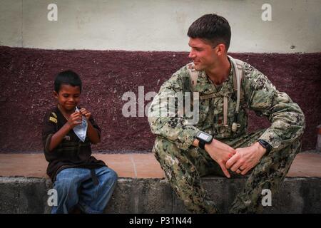 CHOLOMA, Honduras (Aug. 17, 2016) – U.S. Navy Lt. Cmdr. Patrick McKenna, a preventive medicine officer assigned to Navy Environmental Preventive Medicine Unit 2, takes a break with a local child from Choloma’s Monte Verde village during Southern Partnership Station 2016 (SPS-16). SPS-16 is an annual series of U.S. Navy deployments focused on subject matter expert exchanges with partner nation militaries and security forces in Central and South America and the Caribbean. U.S. military teams work with partner nation forces during naval-focused training exercises, military-to-military engagements Stock Photo