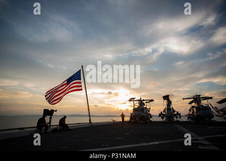 ABOARD USS GREEN BAY (LPD-20), (Aug. 21, 2016) - The sun sets over the USS Green Bay (LPD-20) at White Beach Naval Base, Okinawa, Japan, Aug. 21, 2016. U.S. Marines of the 31st MEU are currently embarked on ships of the USS Bonhomme Richard Expeditionary Strike Group for a scheduled fall patrol of the Asia-Pacific Region. The 31st MEU is the Marine Corps’ only continuously forward-deployed Marine Air-Ground Task Force, and is task-organized to address a range of military operations in the Asia-Pacific region, from force projection and maritime security to humanitarian assistance and disaster r Stock Photo