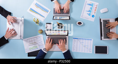 High Angle View Of Businesspeople Analyzing Graphs On Blue Background Stock Photo