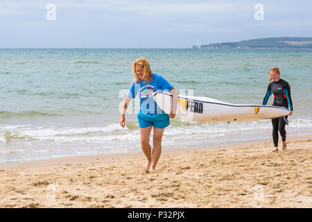 Branksome Chine, Poole, Dorset, UK. 17th June 2018. UK weather: breezy day at Branksome Chine beach, doesn't deter visitors going to the seaside. Women carrying surfski surf ski. Credit: Carolyn Jenkins/Alamy Live News Stock Photo