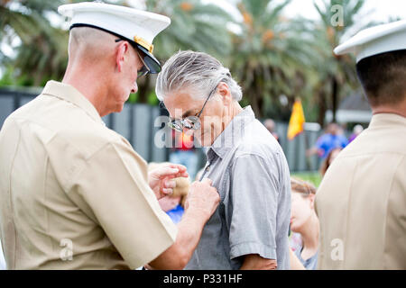 The Commander of Marine Forces Reserve, Lt. Gen. Rex McMillian, (left), pins a pin of honor on the shirt of former Navy Sailor Marlan Maloy, during the wreath laying and commemoration ceremony at the Vietnam Veterans Memorial Moving Wall held in City Park, New Orleans, La., Aug. 27, 2016.  The Moving Wall is a traveling half-size replica of the Vietnam Veterans Memorial that tours the country to honor the men and women who served in the Vietnam conflict. Stock Photo