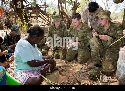 Australian Army soldiers and a US Marine Corps marine are taught rope making skills by a Daly River Aboriginal woman during the training phase of Exercise Kowari 2016, being held in the Daly River region of the Northern Territory, on 31 August 2016. Kowari is an Australian army-hosted survival skills exercise designed to increase defense cooperation between forces from the U.S., Australia and China. (Australian Defence Force photo by Cpl. Jake Sims) Stock Photo