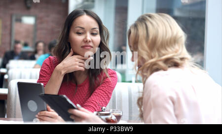 Two beautiful females in cafe using digital tablet Stock Photo