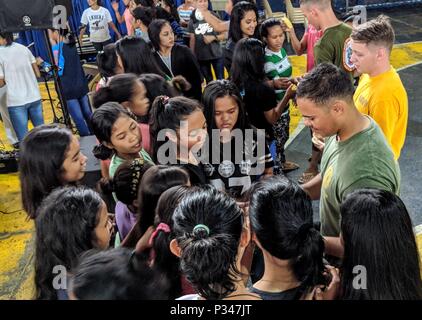 MANILA, Republic of the Philippines (June 12, 2018) Lance Cpl. Justin Major, forefront, Information Systems Technician 2nd Class Justin Greenwell, center, and Lance Cpl. Chandler Hunter pass out stickers to students of the Don Bosco Street Children Village during a community relations project as part of a U.S. 7th Fleet theater security cooperation (TSC) patrol. More than 40 Sailors and Marines from U.S. 7th Fleet staff are currently embarked on USNS Millinocket (T-EPF 3) supporting a range of senior level engagements and community outreach events. (U.S. Navy photo by Mass Communication Specia Stock Photo