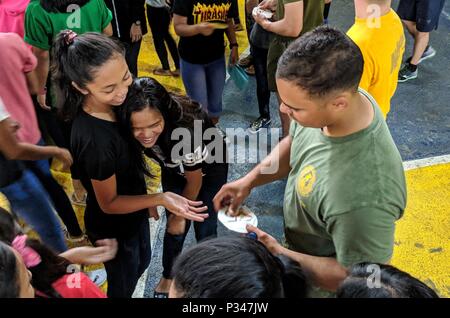 MANILA, Republic of the Philippines (June 12, 2018) Lance Cpl. Justin Major, assigned to Fleet Anti-Terrorism Security Team Pacific (FASTPAC) gives stickers to students of the Don Bosco Street Children Village during a Community Relations Project as part of a U.S. 7th Fleet theater security cooperation (TSC) patrol. More than 40 Sailors and Marines from U.S. 7th Fleet staff are currently embarked on USNS Millinocket (T-EPF 3) supporting a range of senior level engagements and community outreach events. (U.S. Navy photo by Mass Communication Specialist 1st Class Chris Krucke/Released) Stock Photo