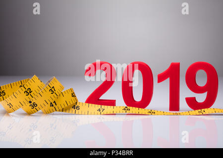 Yellow Measuring Tape Near Year 2019 On Reflective Background Stock Photo
