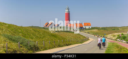 Panorama of a couple riding towards the lighthouse on Texel island, Netherlands Stock Photo