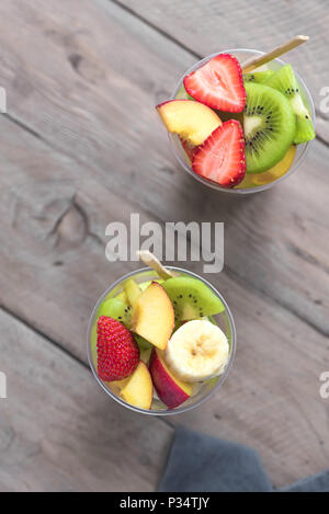 Fruit salad in plastic cups takeaway. Sliced organic fruits and berries, healthy snack to go, copy space. Stock Photo