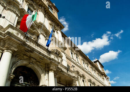 Italian and EU flags on a balcony of the italian army academy with blue sky and white clouds. Modena, Italy Stock Photo
