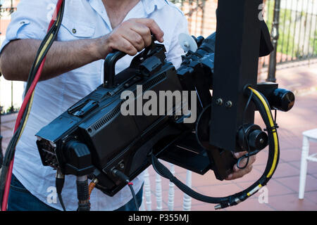 Cameraman checking equipment of camera in broadcast television green screen virtual studio room. Stock Photo