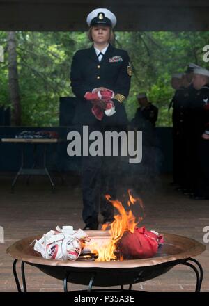 BANGOR, Wash. (June 14, 2018) Chief Hospital Corpsman Farrah Ocasio, from Detroit, Michigan, assigned to Trident Training Facility in Bangor, Wash., walks the remains of a U.S. flag to a fire during a flag retirement ceremony at Naval Base Kitsap - Bangor. When a U.S. flag becomes worn, torn, faded, or badly soiled, the flag should be retired with the dignity and respect befitting it. The traditional method is to cut the flag into pieces, separating the 13 stripes from canton and incinerating them separately in a respectful manner. (U.S. Navy photo by Mass Communication Specialist 1st Class Am Stock Photo