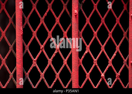 An abstract shot of fine red painted wire lattice on a barred window in Johannesburg inner city Stock Photo