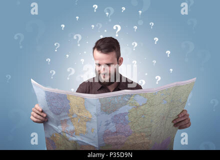 Handsome young man holding a map with white question marks above his head Stock Photo