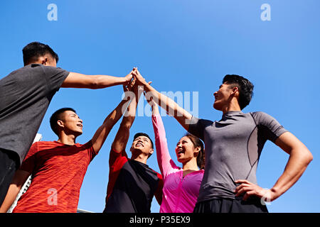 team of asian young adult sportsmen and sportswoman putting hands together to show unity and teamwork spirit. Stock Photo