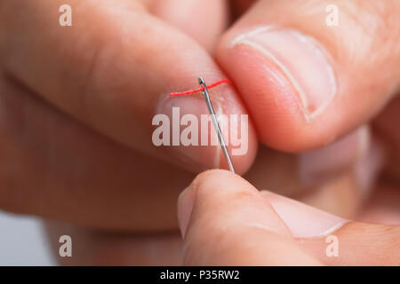 Close up hand holding the red threaded with stitching needles. Select focus shallow depth of field and blurred background. Stock Photo