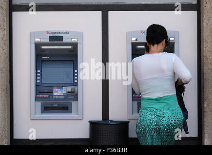 Unidentified girl withdrawing money from an ATM machine in city center. More than 4,000 ATM machines has been installed across Croatia since 1990. Stock Photo
