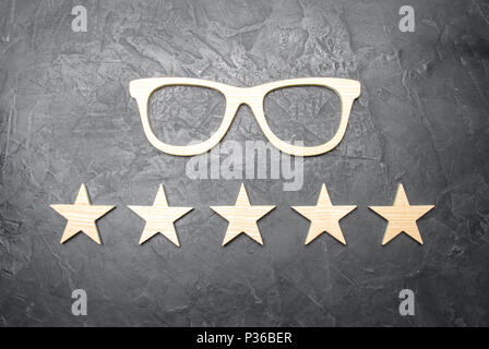 Wooden glasses and five stars on a concrete background. High quality glasses. The best optics. Correction of vision, rating of points and stores for t Stock Photo