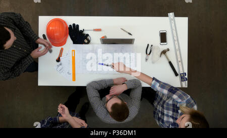 Group of young architects working on drawings and making measurements with ruler and divider Stock Photo