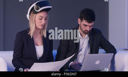 Two business people with VR headset and laptop discussing construction project Stock Photo