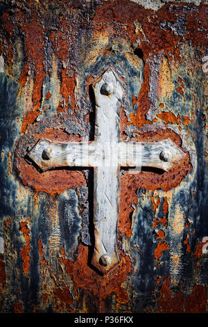 Old Christian cross with dramatic, rusty metal gloomy background with cracked, peeling paint Stock Photo
