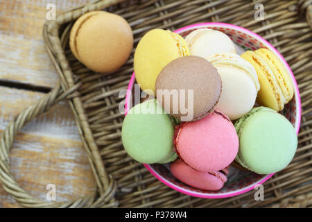 Colorful macaroons in bowl on wicker surface Stock Photo