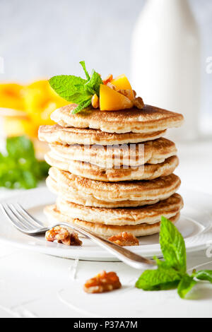 Bunch of pancakes with poached peaches and nuts Stock Photo