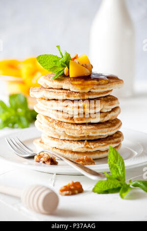 Bunch of pancakes with poached peaches and nuts Stock Photo