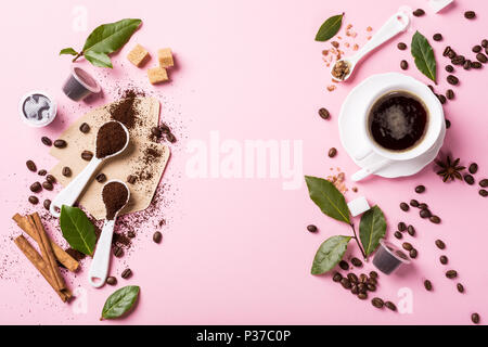 Food background with ground coffee in spoons, coffee beans, espresso cup, ground and capsules, green leaves, copy space, top view. Stock Photo