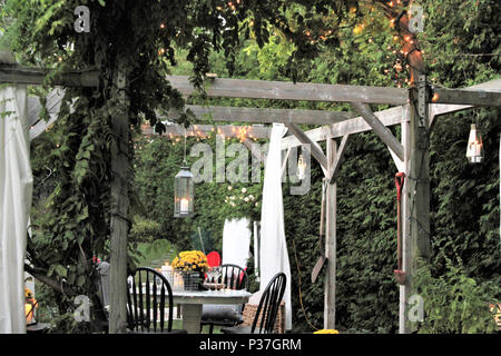 Outdoor dining area with overhead arbour, greenery and lights Stock Photo