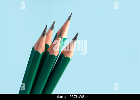 Few of classic graphite sharply sharpened pencils, in green wooden shell, on  blue background. Stock Photo
