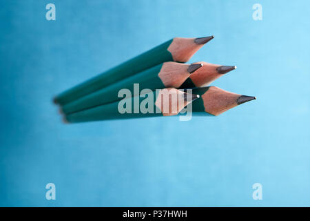 Group of simple graphite pencils in a wooden shell turquoise color on blue background. Stock Photo