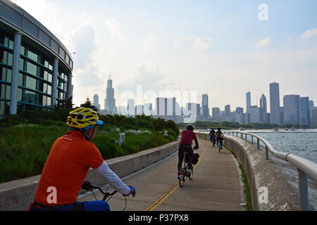 Chicago's skyline appears as cyclists ride the lakefront bike path on the back side of the Shedd Aquarium on Lake Michigan and the Museum Campus Stock Photo