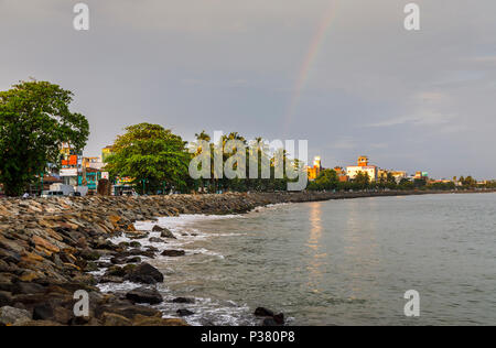 Rocky seafront promenade and coastline of Galle, Southern Province, Sri Lanka, with dark clouds and threatening weather in evening light with rainbow Stock Photo