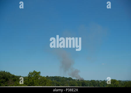 clubs of blue smoke rise from the burned down pyrene building destroyed by fire Stock Photo