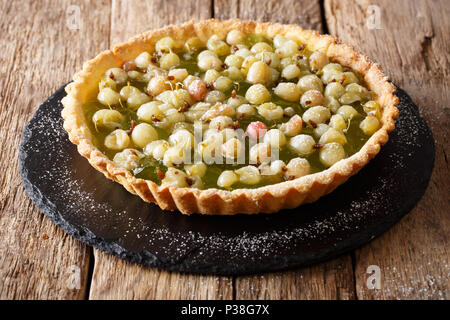 Summer berry tart with gooseberries close-up on a slate plate on a table. horizontal Stock Photo