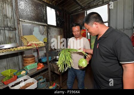 (180618) -- NANCHANG, June 18, 2018 (Xinhua) -- Zou Yujiang (R) asks about the price of vegetable at a restaurant along the National Highway 206, June 12, 2018. Zou has to spend every penny wisely because of the limited budget on the road. Zou Yujiang, 41 years old, is a truck driver from Gao'an City of Jiangxi Province. He has spent most of his time on the road, transporting goods from one place to another. There have been over 21 million employees in the industry of the road freight transportation in China so far. Like Zou Yujiang, most of them make a living on trucks with little time stayi Stock Photo