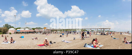 Panorama of Blue Moon Beach, Lido di Venezia, Venice, Veneto, Italy in late spring with the pier and restaurants, people swimming and sunbathing Stock Photo