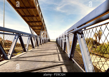 blue steel bridge across the road for people and bycles in Guardamar del segura, Alicante. Spain Stock Photo