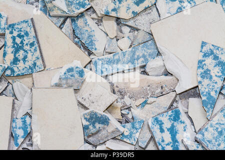 Broken tiles from demolition of old flooring. Texture of worn retro floor pieces. Ceramic shards close-up as background. Idea modernization of tiling. Stock Photo