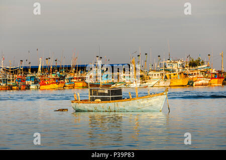 Traditional local style small fishing boat moored in the colourful harbour at the fishing port of Weligama on the south coast of Sri Lanka Stock Photo